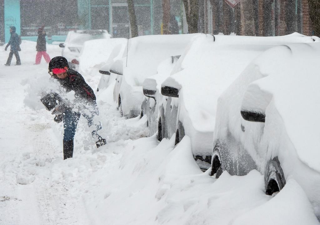 A woman shovels out her car during a snowstorm, Friday, February 7, 2020 in Montreal.