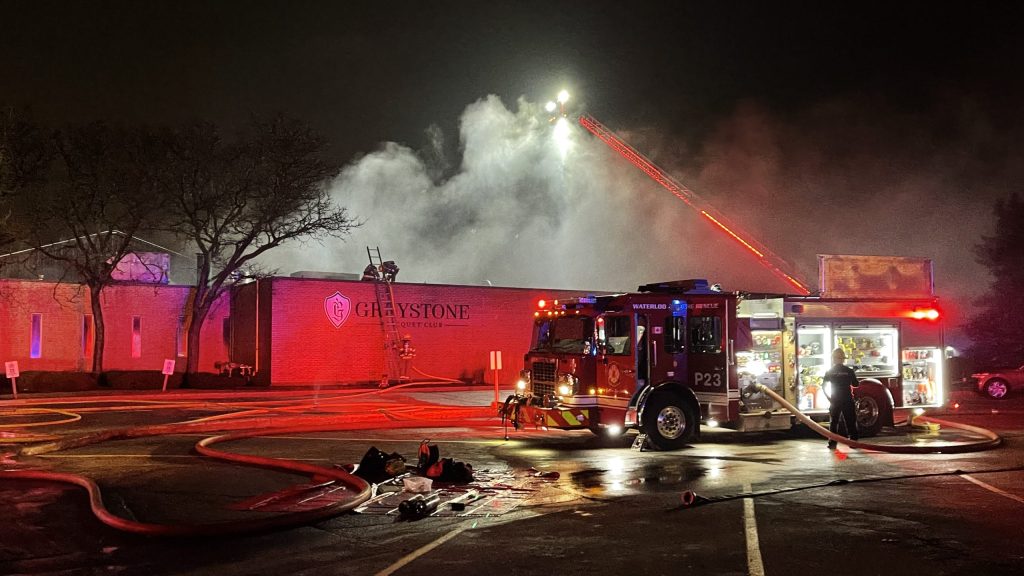 A fire engine with Waterloo Fire sits illuminated in front of Greystone Club.
