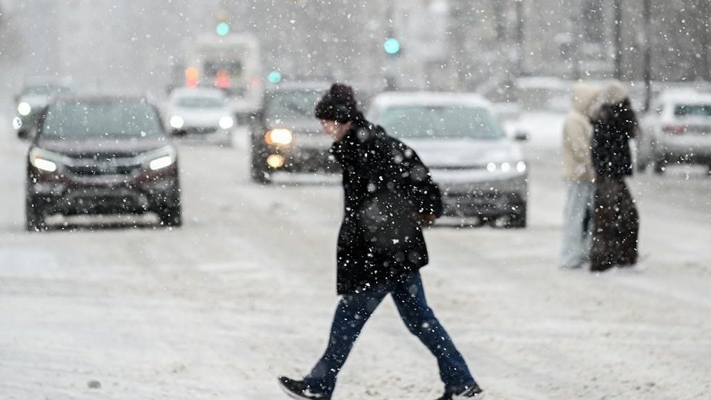 A person crosses a street as snow falls.(THE CANADIAN PRESS/Graham Hughes)