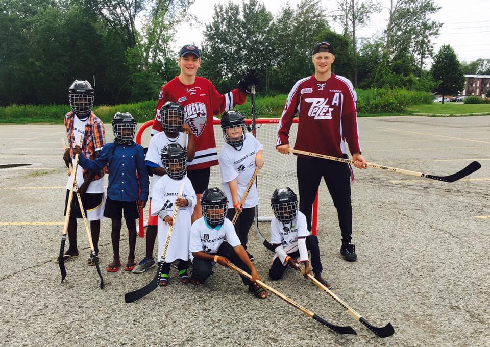 Steven Lorentz, alongside Nate Schnarr, teaching new Canadians from Africa how to play road hockey