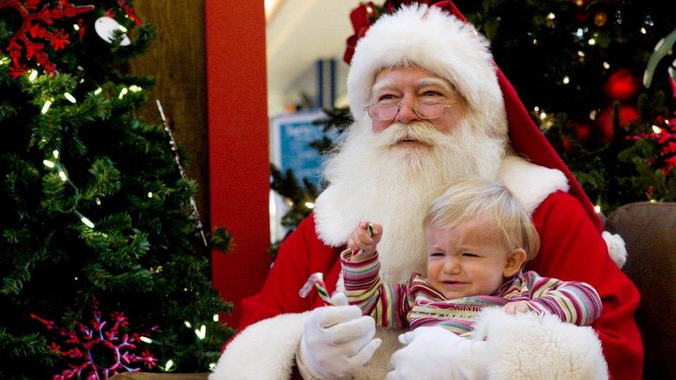 A child reacts as she sits with Santa Claus for a photo at a mall in Toronto on Friday December 10, 2010.