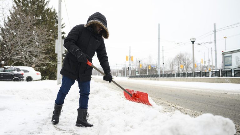 A person shovels snow from their driveway following a winter storm that affected southern Ontario. (THE CANADIAN PRESS/Christopher Katsarov)