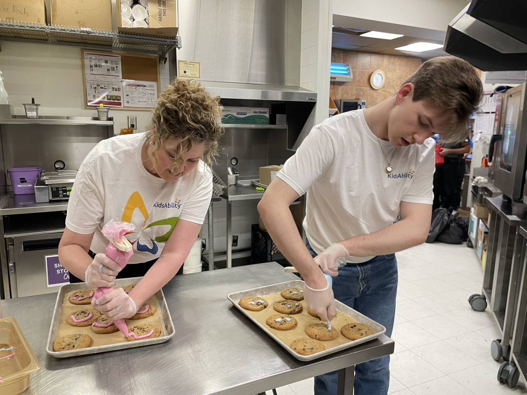 Two people decorating smile cookies at Tim Hortons
