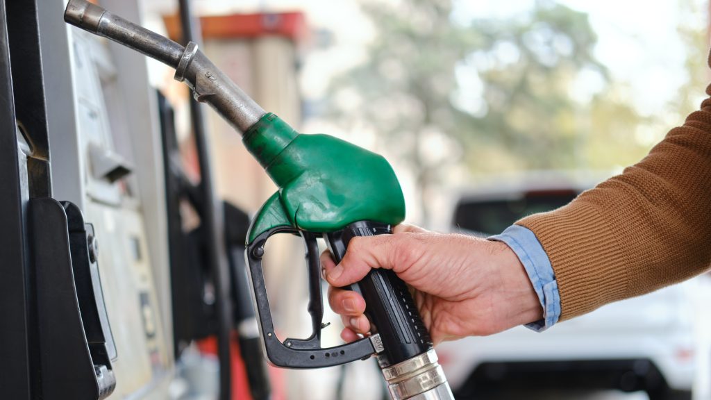 Close-up of a hand holding a green fuel pump nozzle, refueling a car at a gas station. Photo: Getty Images.
